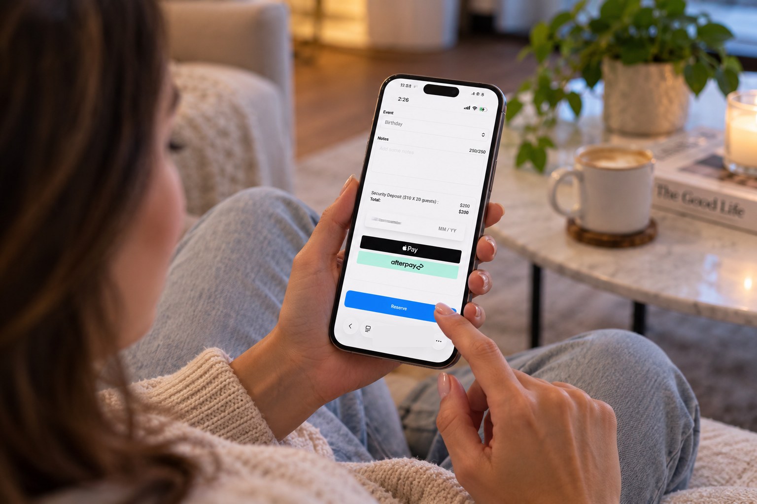 A guest at home paying a security deposit for a birthday booking on her phone, with Apple Pay and Afterpay as payment options