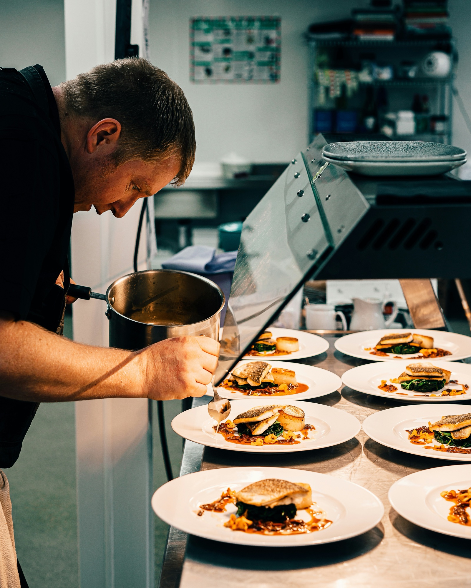 A chef plating dishes at the kitchen pass