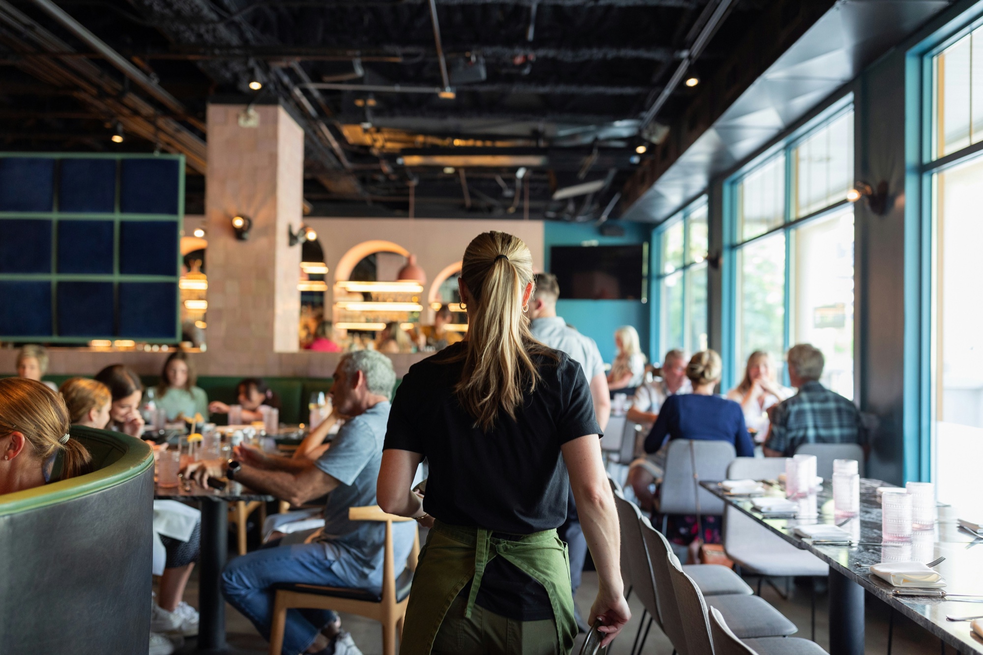 A waiter crossing a busy restaurant dining room